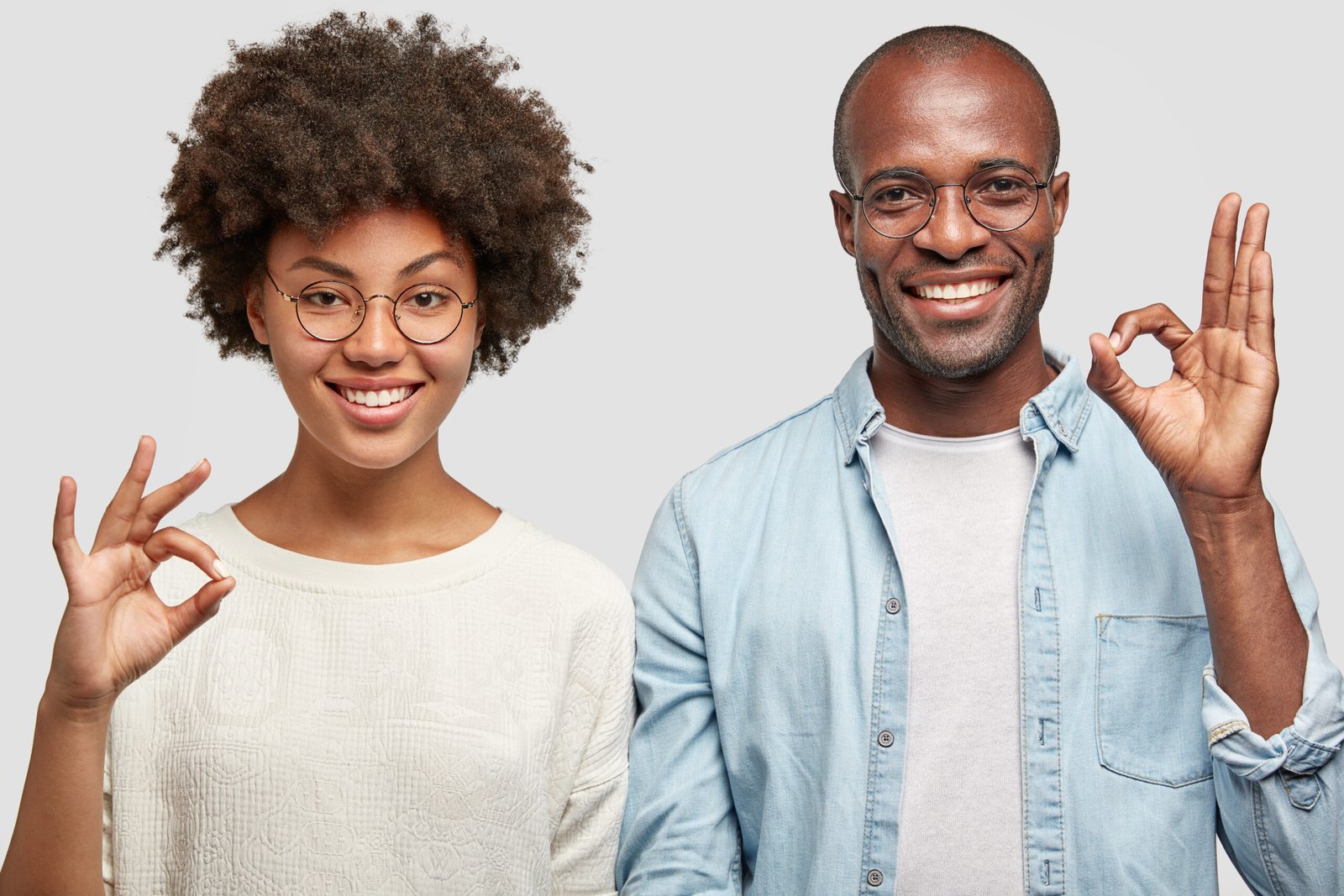 Cheerful African American Couple Make Okay Gesture, Have Positive Expressions, Show Approval Or Agree With Plan, Dressed In Casual Clothes, Isolated Over White Background. Body Language Concept